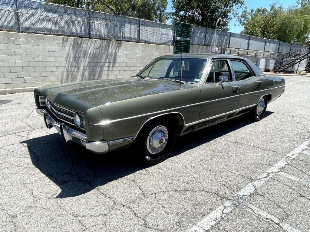 A vintage dark green four-door sedan parked on a street.