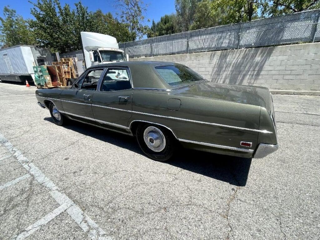 Classic green vintage car parked outdoors on a sunny day.