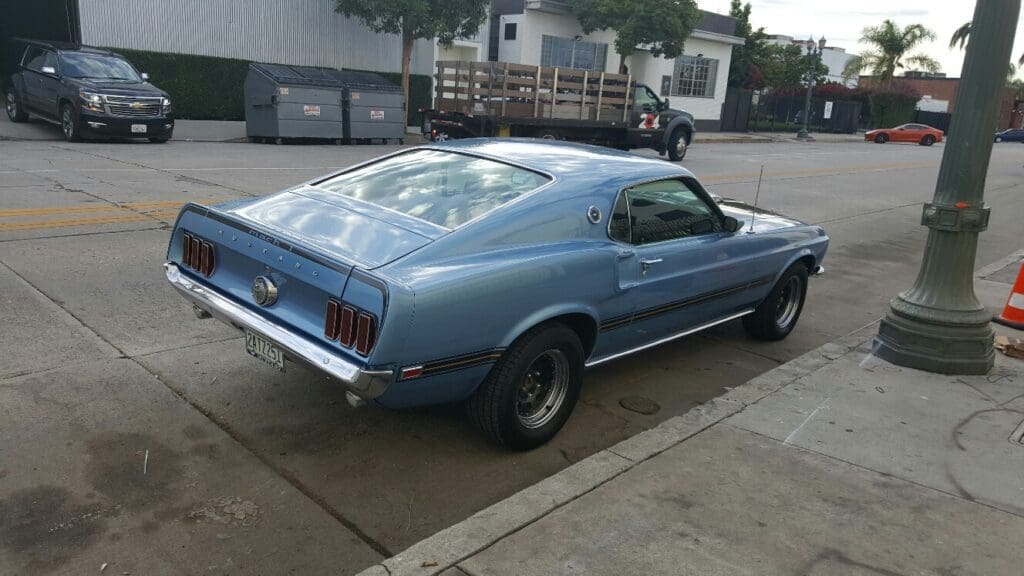 Classic blue Ford Mustang parked on a wet driveway.