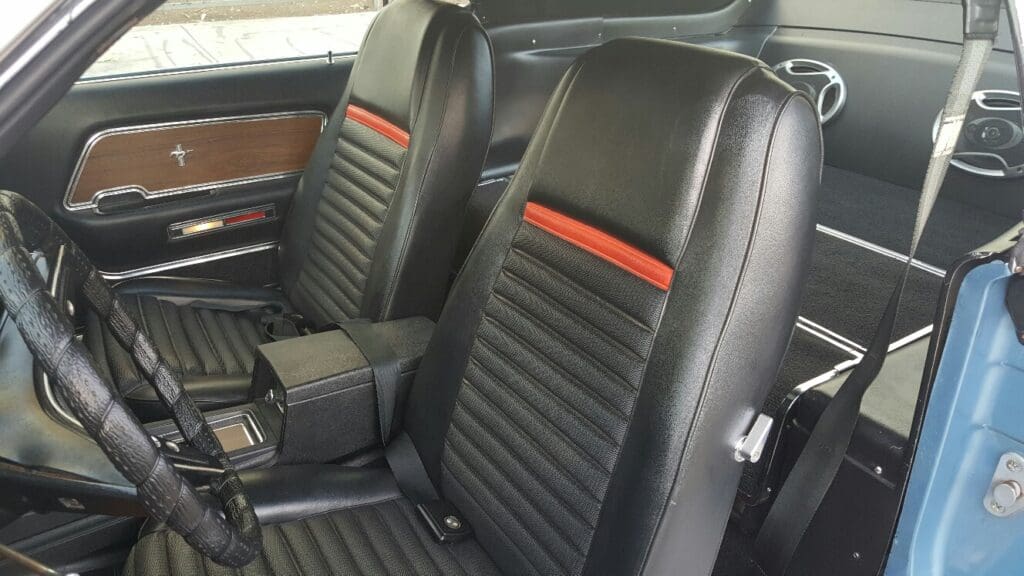 Black leather car seats with red stripe accents and ribbed design.