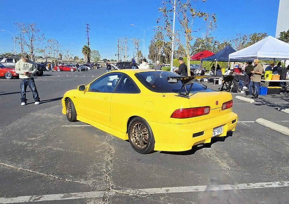 Bright yellow sports car parked at an outdoor event under clear skies.