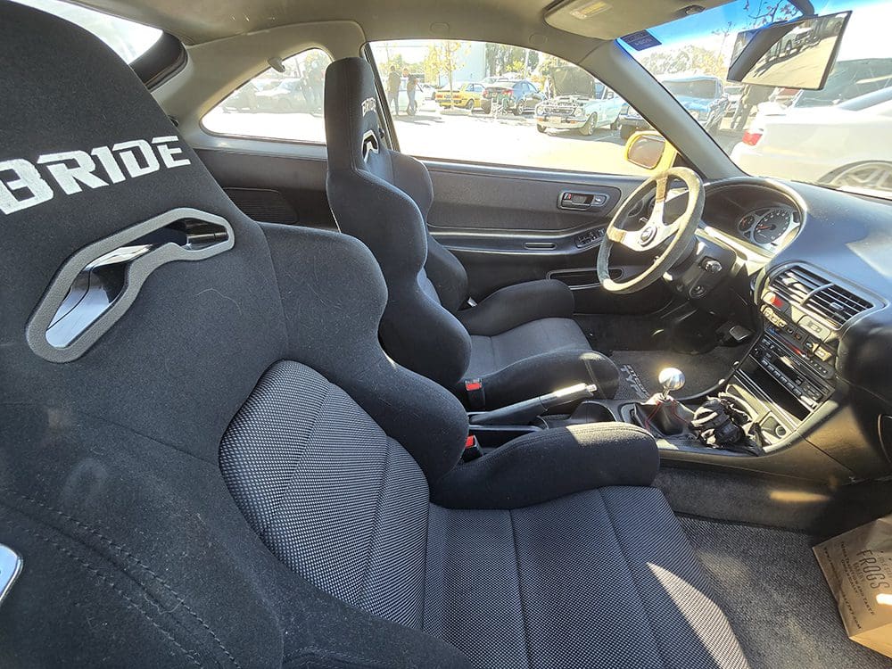 Interior of a classic sports car with racing seats and a manual transmission.