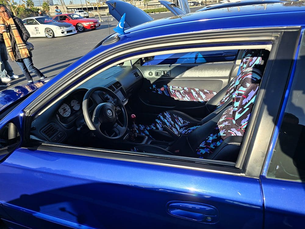 Interior view of a blue car showing the driver's seat and steering wheel.