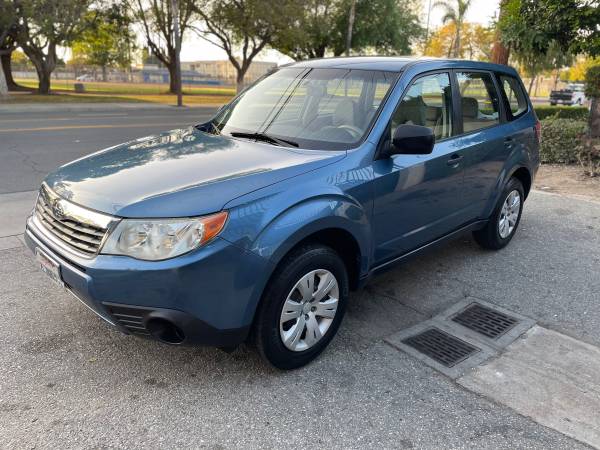 Blue SUV parked on a driveway beside trees.