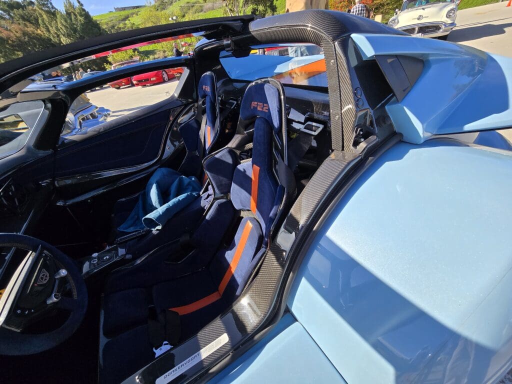 Interior and partial exterior view of a blue convertible car with black and orange seats.