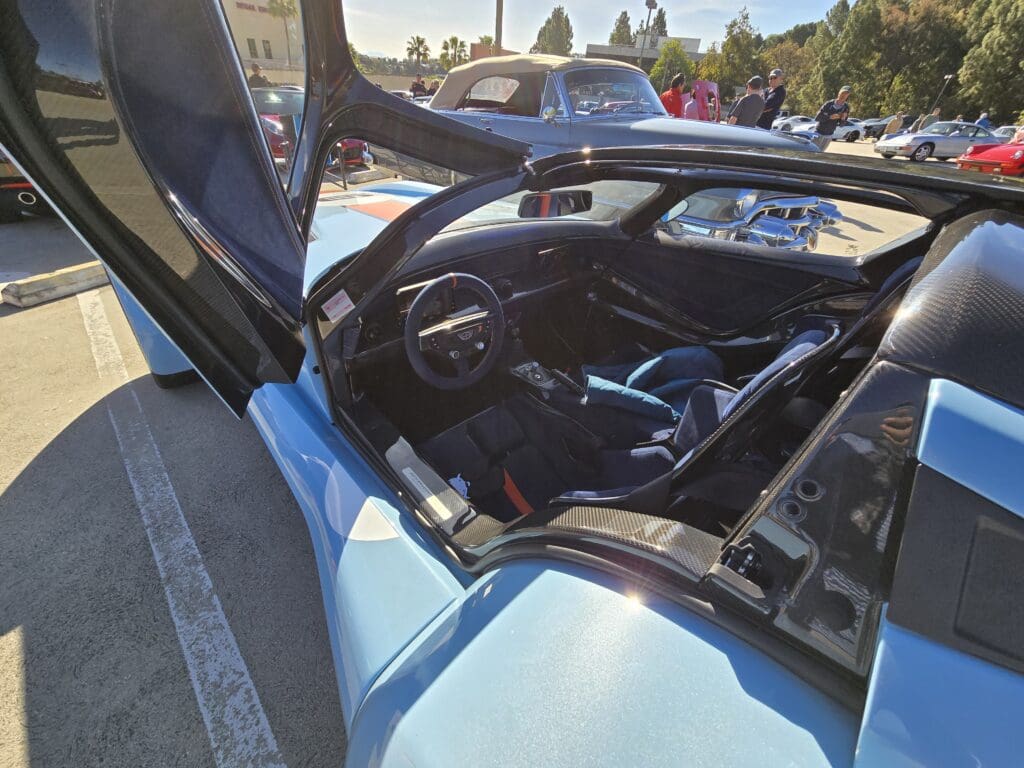 Sports car with gullwing doors open, showing interior details.