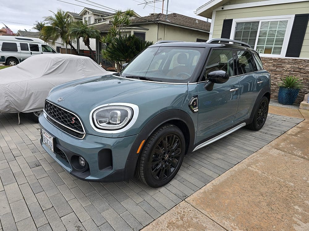 A blue Mini Cooper parked on a residential driveway.