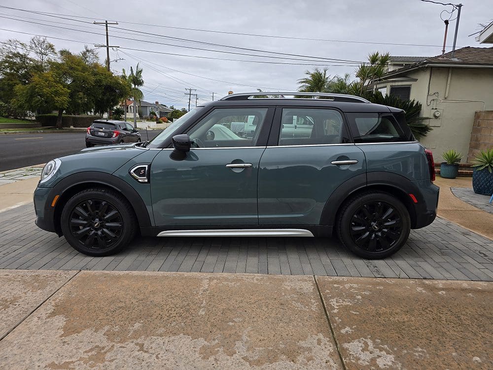 A green Mini Cooper parked on a residential street.