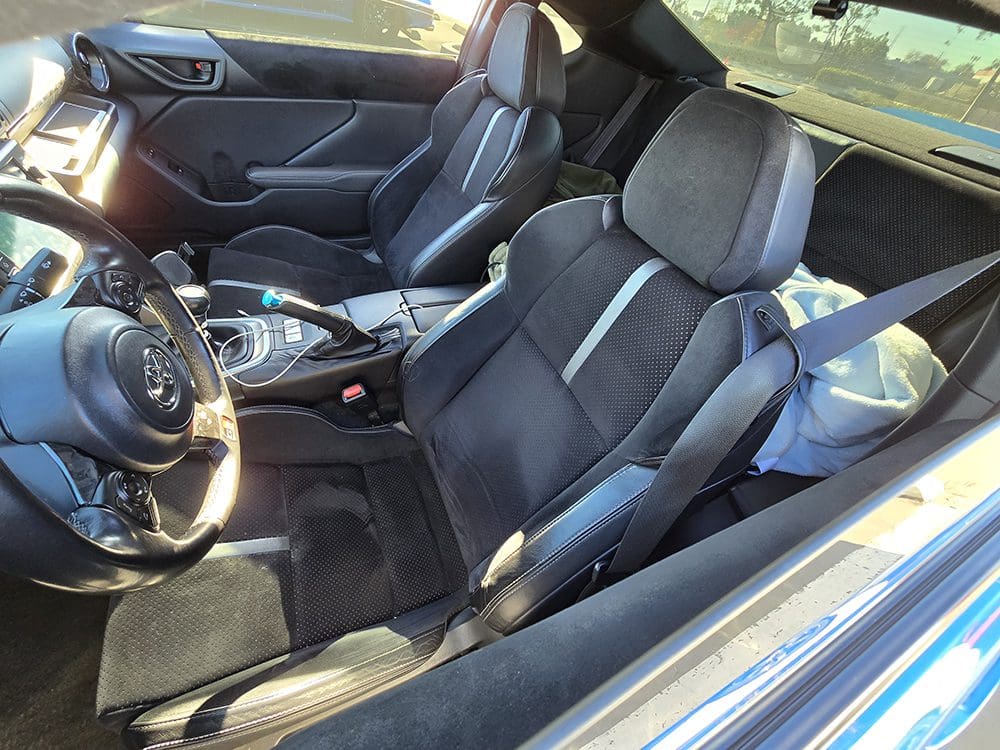 Interior view of a modern car showing black sports seats and steering wheel.