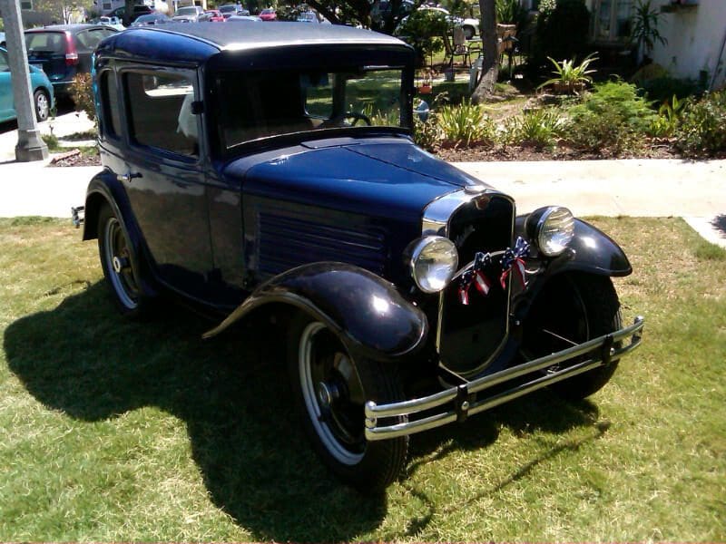 A classic vintage car parked on grass in daylight.