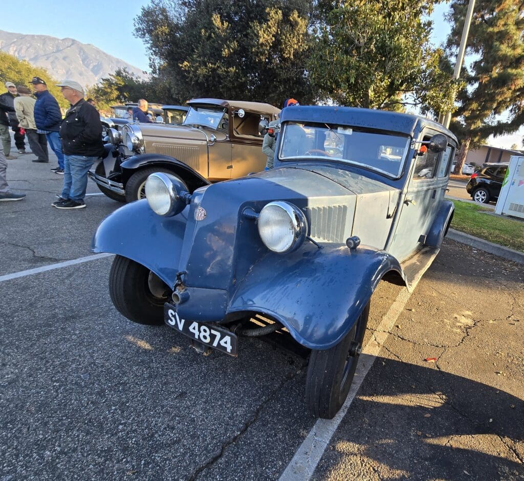 Vintage blue and beige classic car parked outdoors at a sunny event.