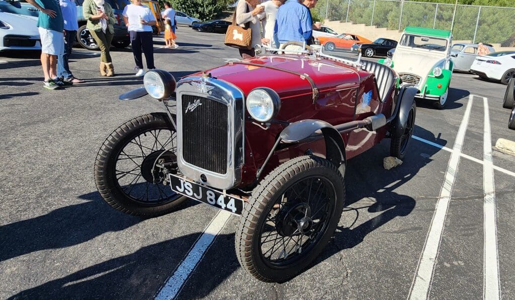 Vintage red race car parked outdoors with large tires.