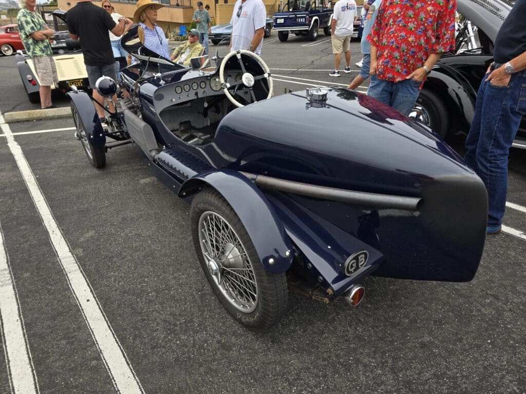 A vintage three-wheeled car with a sleek black body at a car show.