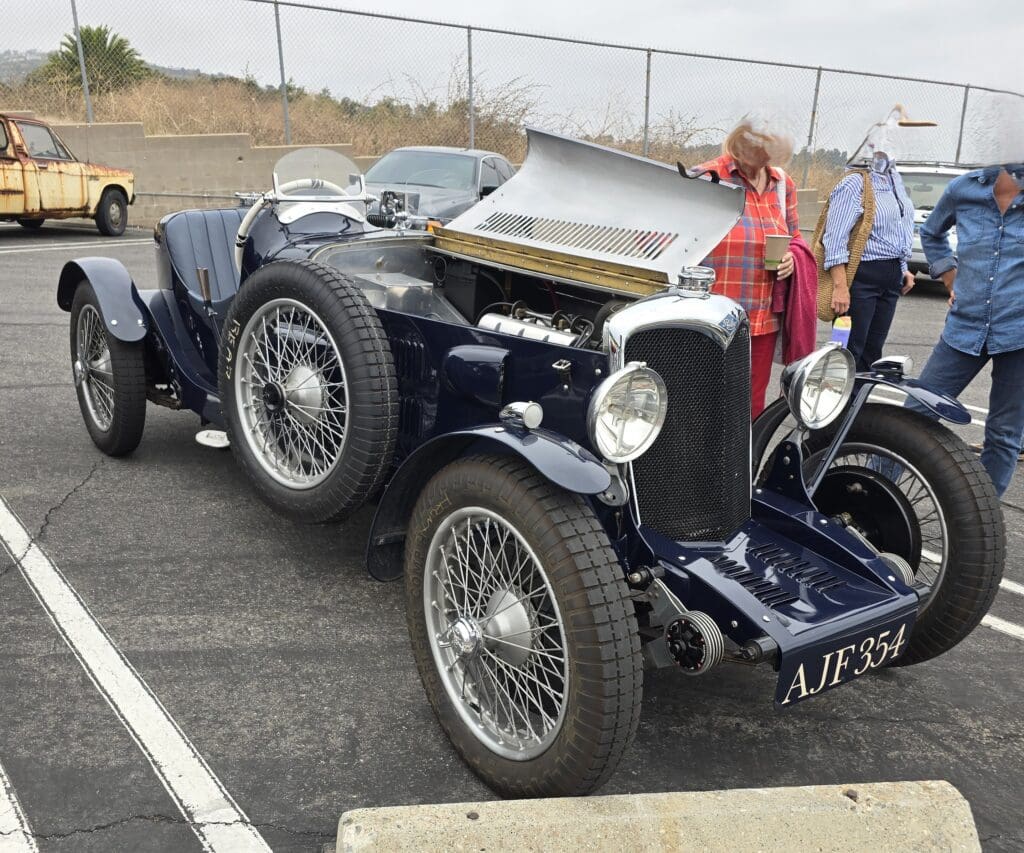 A classic vintage car displayed outdoors with a man admiring it.