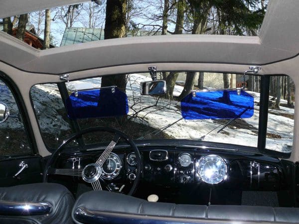 View from inside a vintage car showing dashboard and steering wheel.