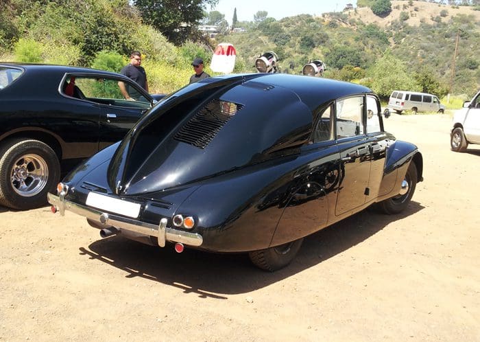Rear view of a sleek, black vintage car with unique teardrop design.