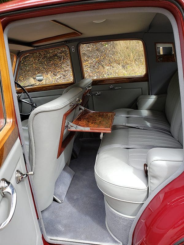 Vintage car interior with elegant leather seats and wooden folding tray.