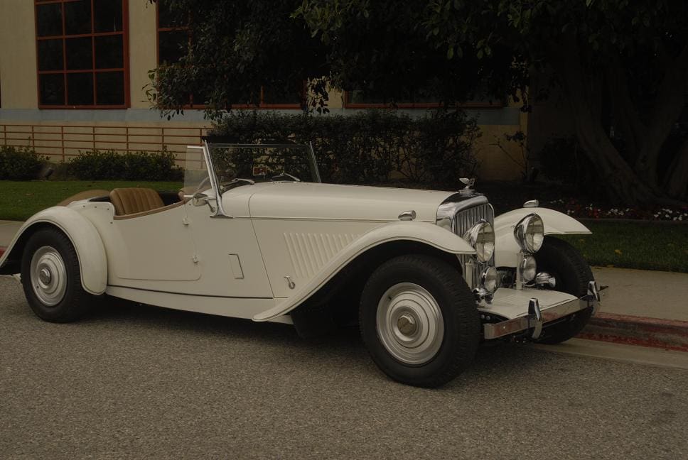 Classic white vintage convertible car parked on a street at night.