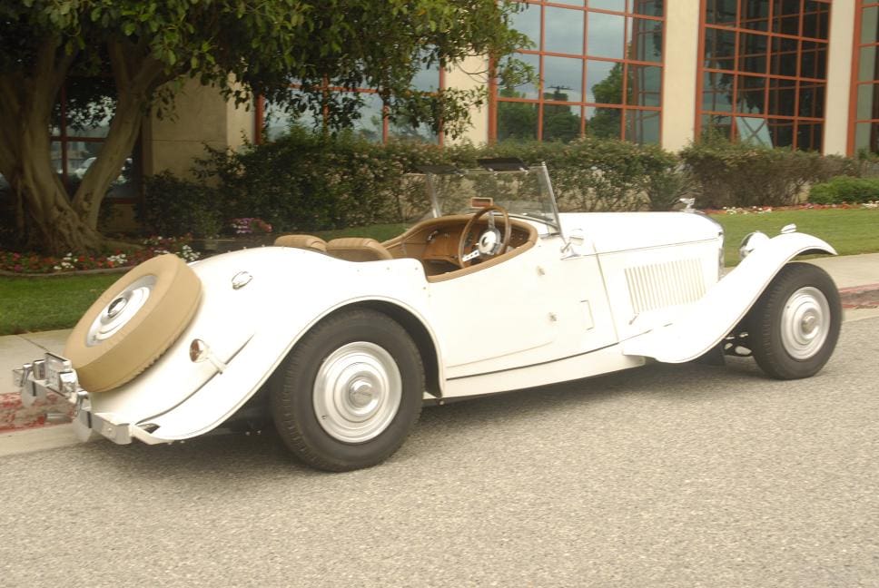 Classic white vintage convertible car parked outdoors.