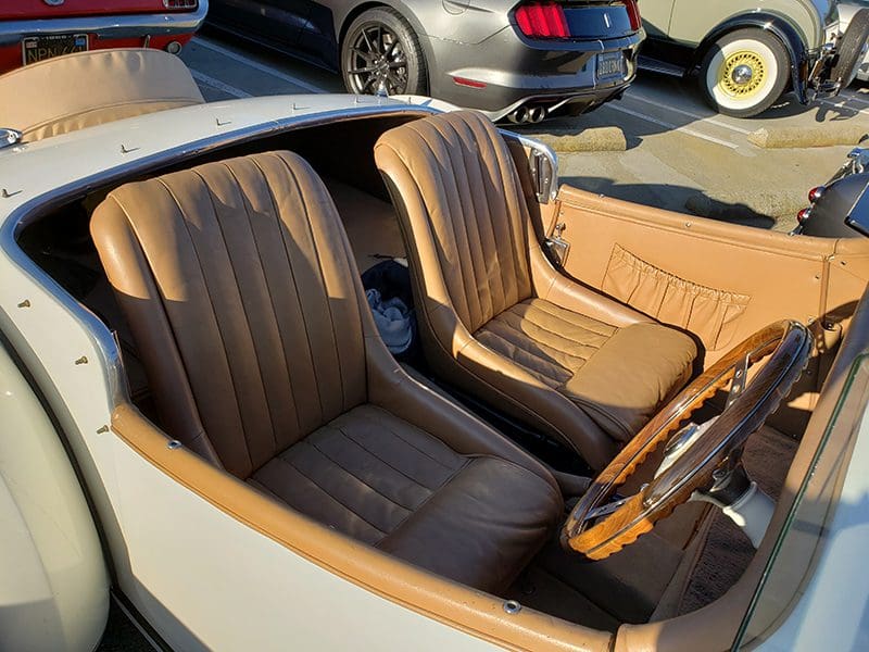 Classic car interior with brown leather seats and wooden dashboard.