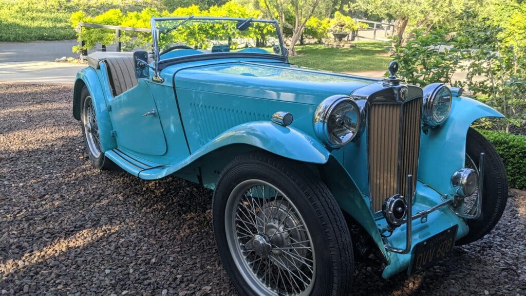 Vintage blue convertible car parked outdoors on gravel.