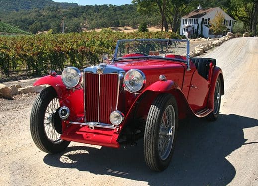 Classic red vintage convertible car parked on a sunny road.