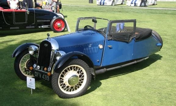 Vintage blue convertible car with white-walled tires on grass.