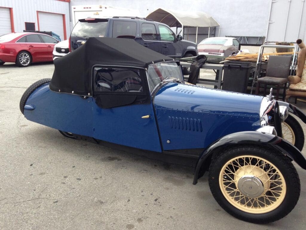 A vintage blue convertible car with a black soft top.