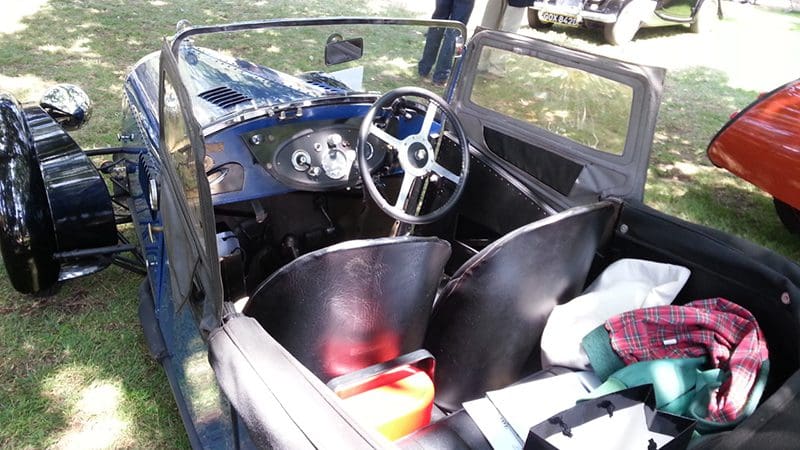 Interior of a vintage car showcasing its steering wheel and dashboard.