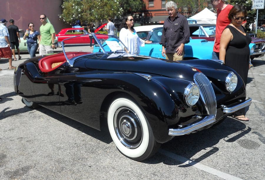 Classic black convertible car with whitewall tires at a car show.