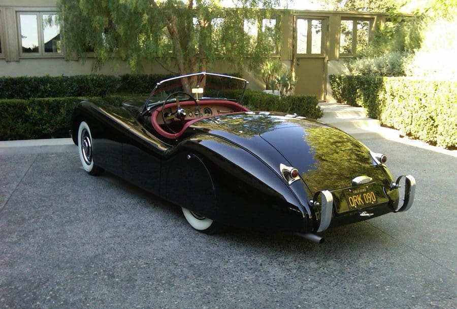 A sleek black vintage convertible car with red interior.