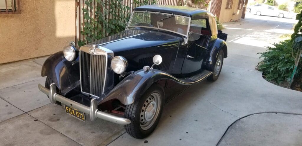 Classic black vintage convertible car with beige soft top.