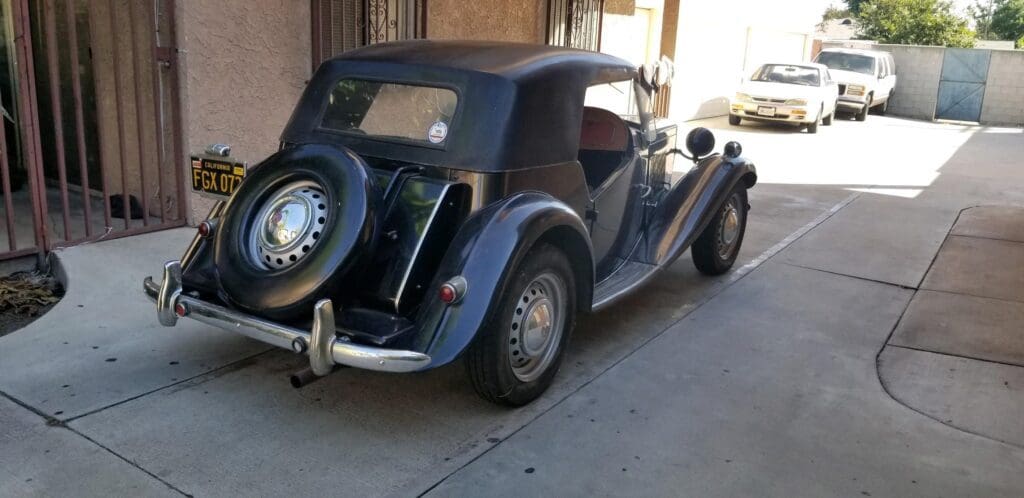 Vintage convertible car parked in a garage with a black soft top.