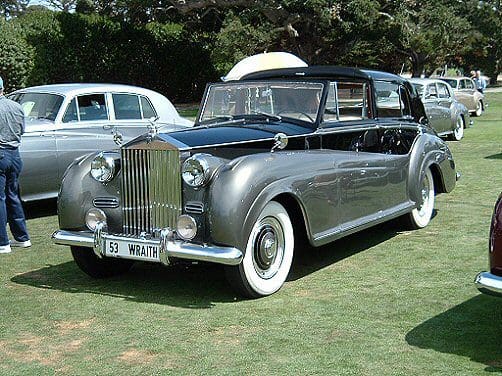 Classic luxury convertible car parked on grass.