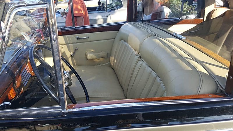 Vintage car interior with cream leather seats and wood trim.