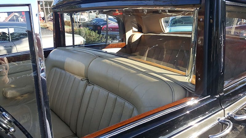 Interior view of a vintage car with beige leather seats and wooden accents.