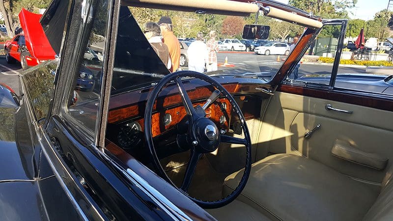 Classic car interior with vintage steering wheel and dashboard.