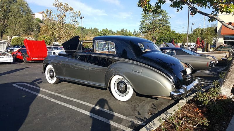 Classic black convertible car parked outdoors on a sunny day.