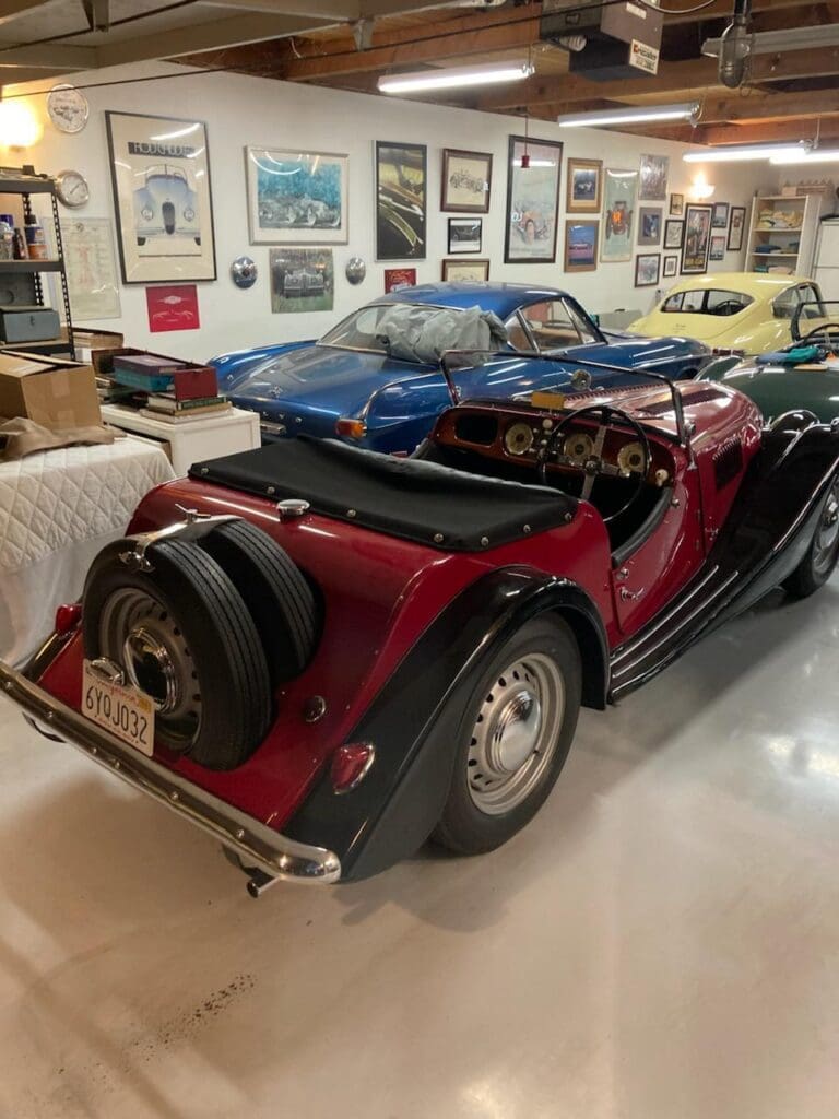 A vintage red convertible car displayed indoors with a spare tire on the back.