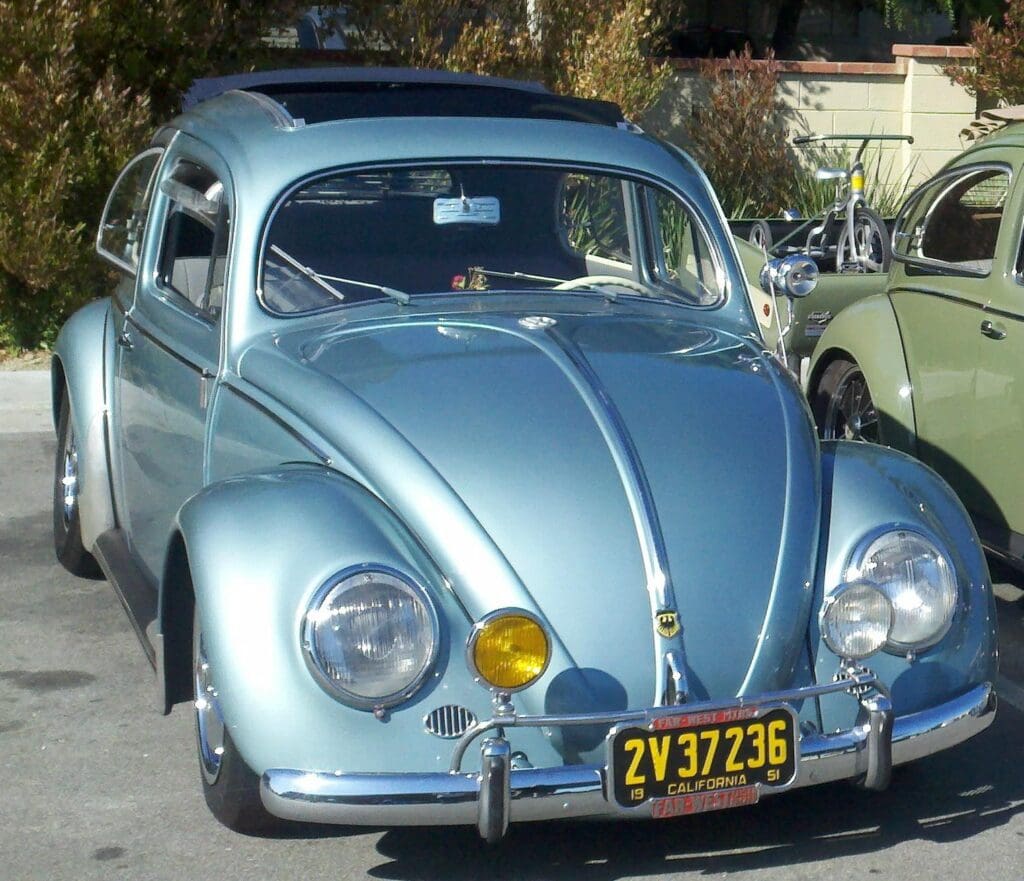 A shiny vintage blue Volkswagen Beetle parked outdoors.