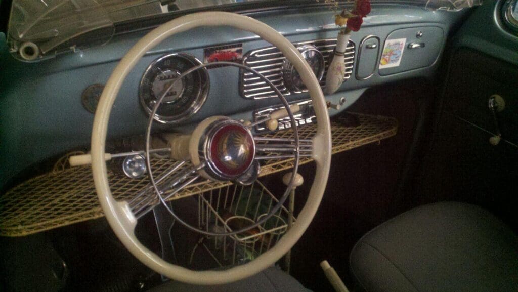 Vintage car dashboard with classic steering wheel and radio.