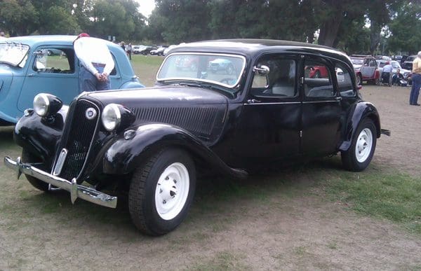 Classic vintage black car with white rims parked on grass.