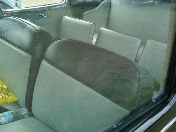Inside view of a car's backseat with fabric upholstery and a seatbelt.