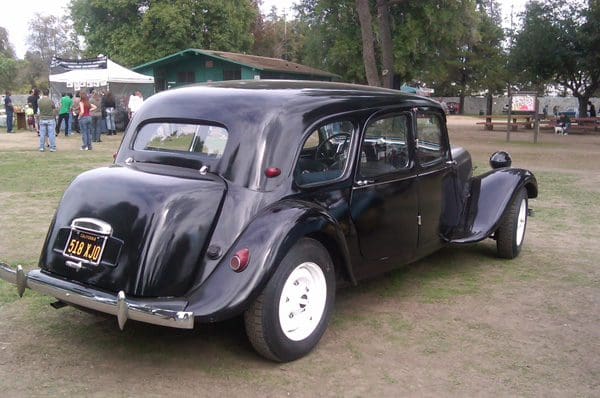 Classic black vintage car with whitewall tires parked outdoors.