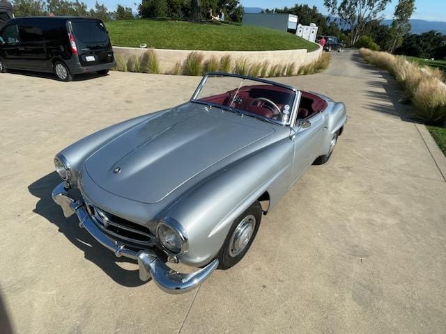 Classic silver convertible parked on a sunny driveway.