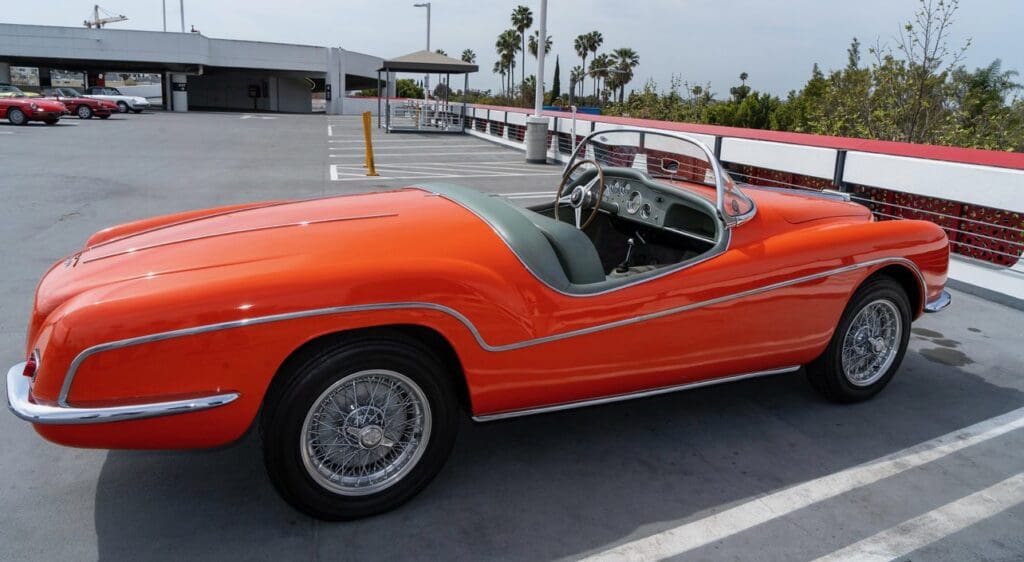 Bright orange classic convertible car parked on rooftop.