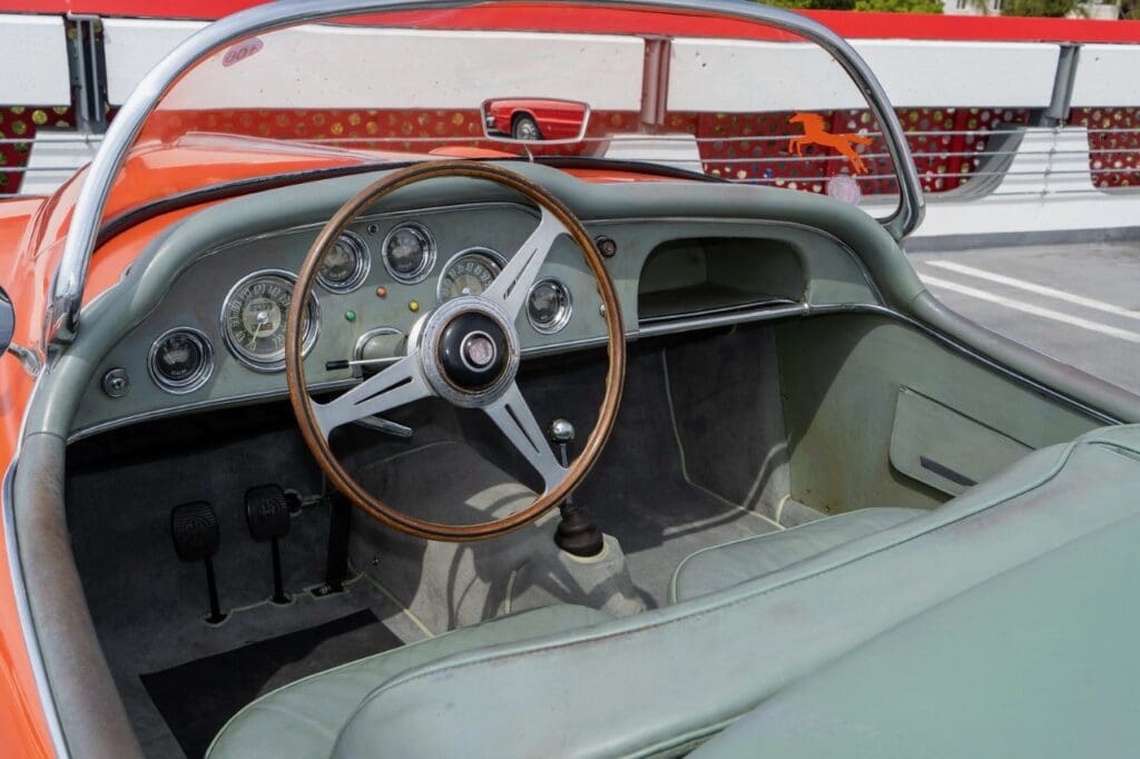 Classic car interior with wooden steering wheel and vintage dashboard.