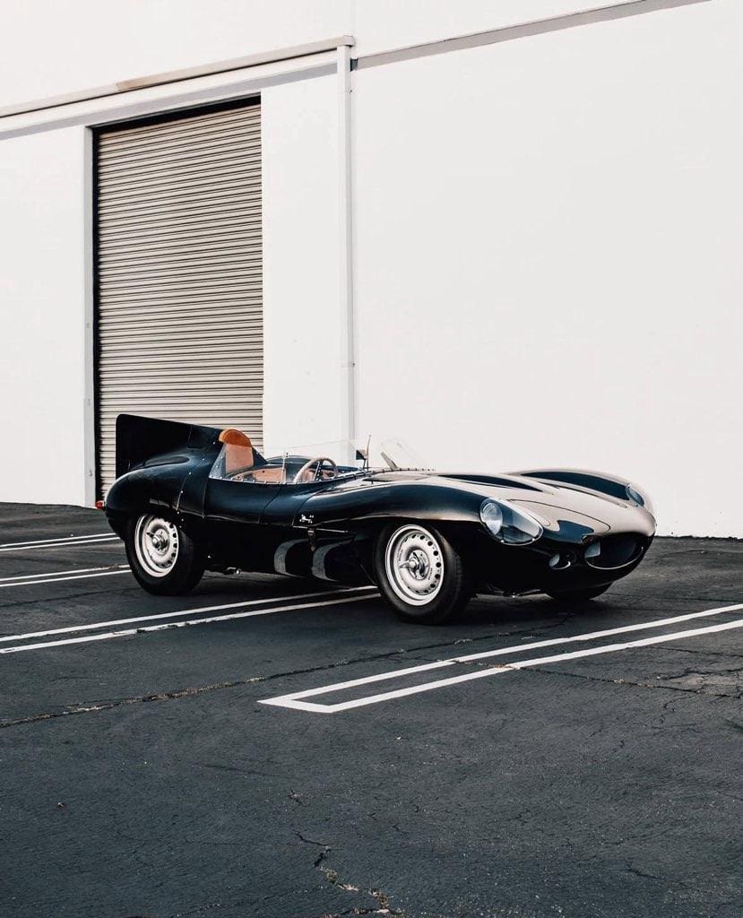 Classic black convertible sports car parked outside a building.