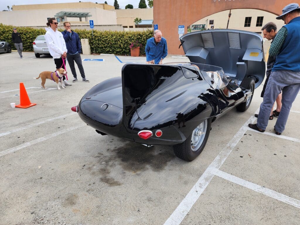 Classic black vintage car with open rear hood at a car show.