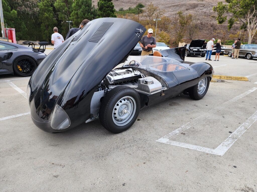 Classic silver sports car with open front hood revealing engine.